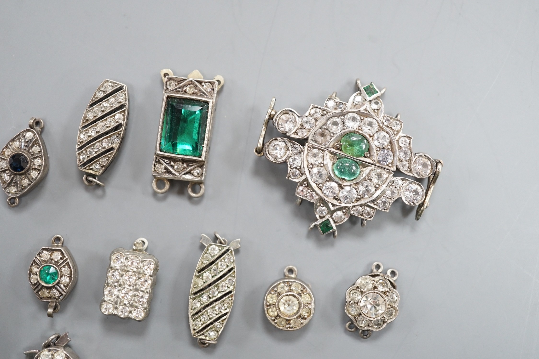 A small group of assorted white or base metal and paste set clasps.